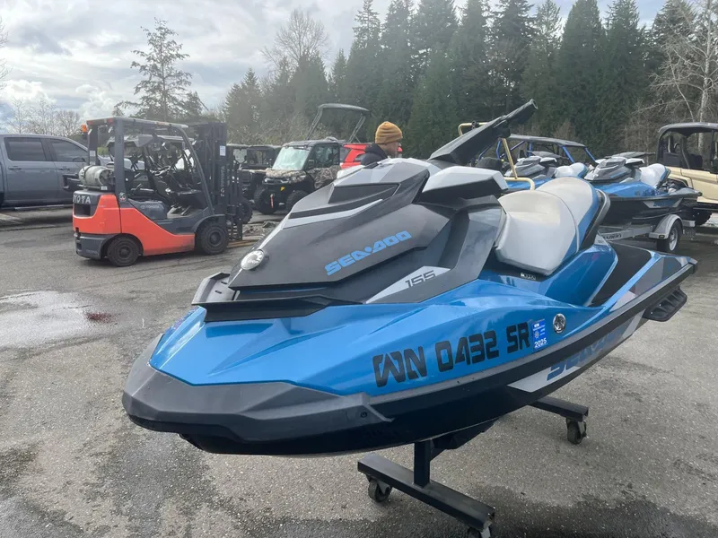 Slide: The Image of 2018 Sea-Doo GTI SE 155 jet ski in a parking lot with forklifts and trees. - 3