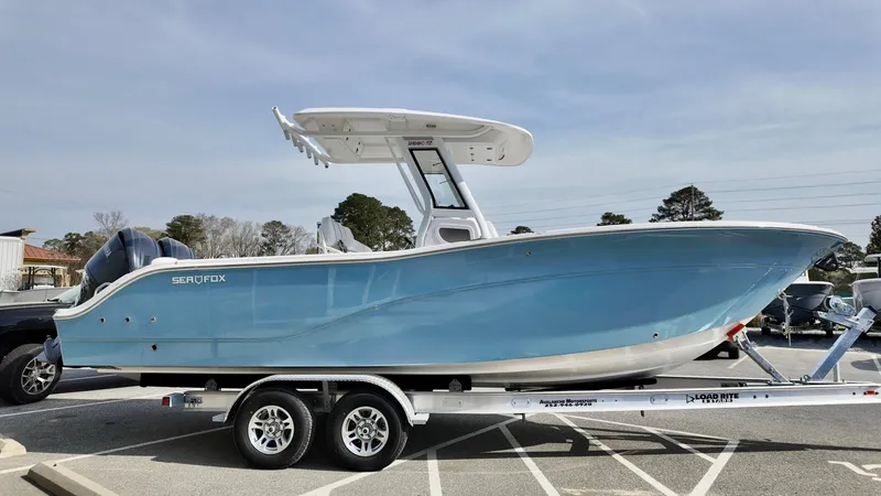 Slide: The Image of 2025 Sea Fox 268 Commander boat on trailer, light blue hull, parked outdoors. - 1