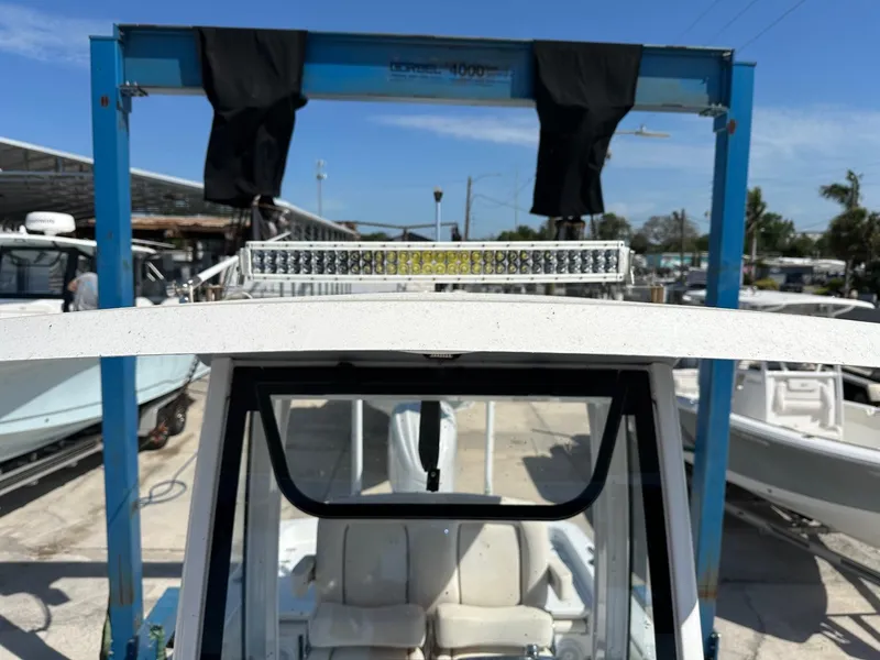 Slide: The Image of 2022 Sea Hunt BX 25 FS boat under a blue hoist in a marina. - 12