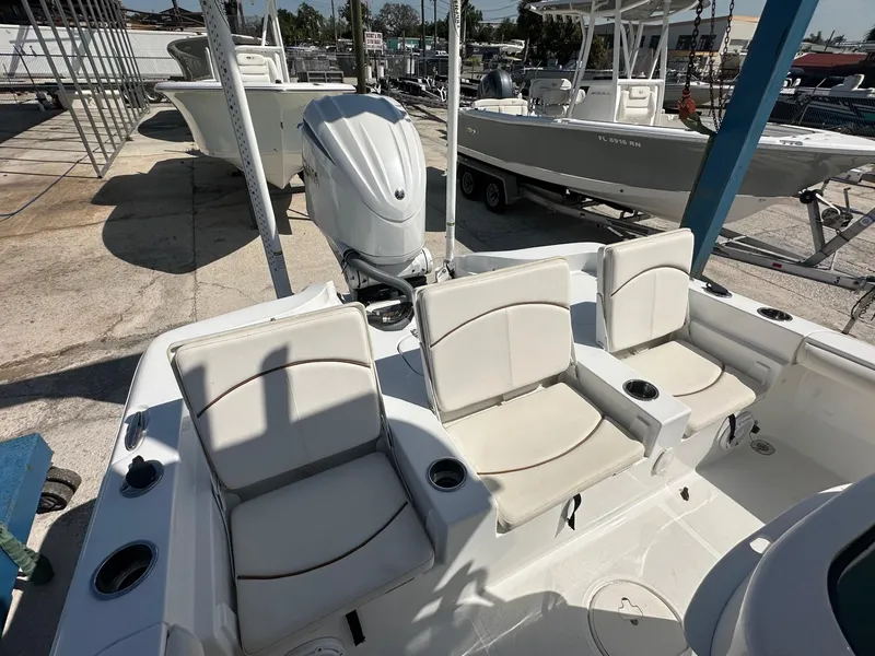 Slide: The Image of 2022 Sea Hunt BX 25 FS boat with cushioned seating and outboard motor in a marina. - 15