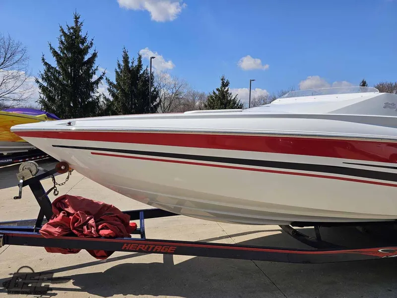 Slide: The Image of 2008 Baja 23 Outlaw boat on trailer, red and white design, parked outdoors. - 19
