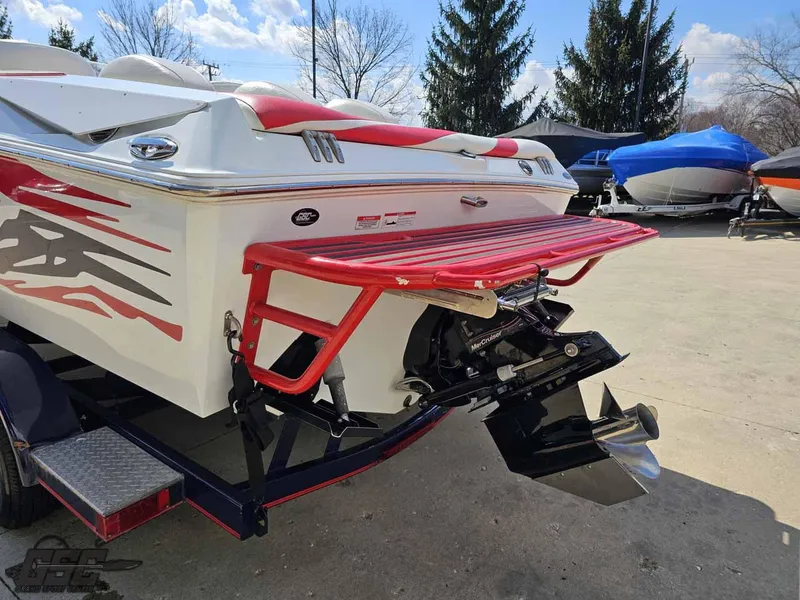 Slide: The Image of 2008 Baja 23 Outlaw boat with red accents and trailer, parked outdoors. - 36