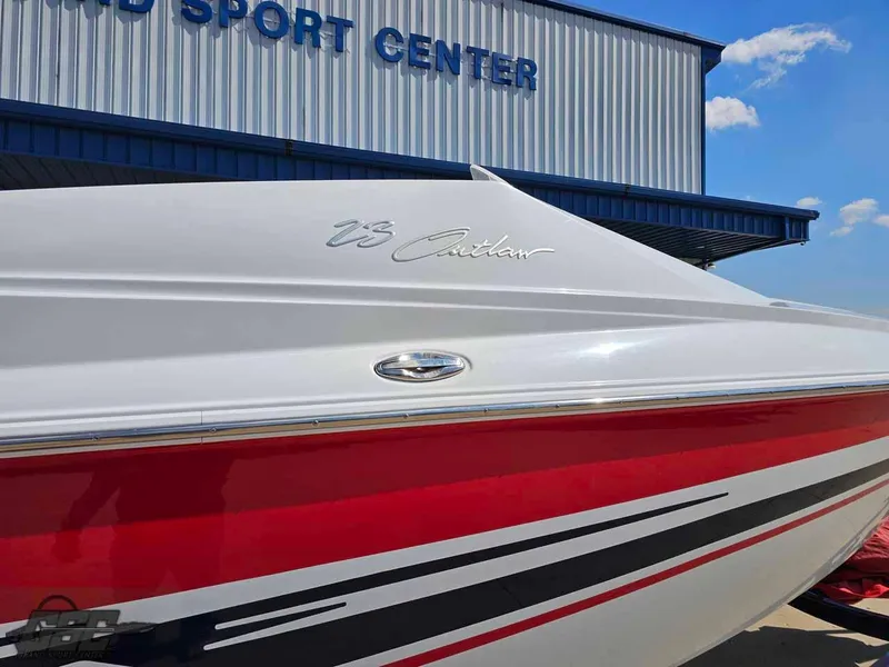 Slide: The Image of 2008 Baja 23 Outlaw boat with red and white design near a sports center. - 8