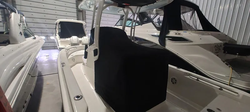 Slide: The Image of 2023 Boston Whaler 220 Dauntless boat in storage, featuring sleek design and covered seating. - 13