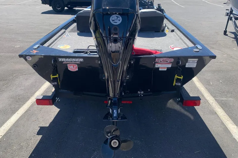 Slide: The Image of 2024 Tracker PRO170 boat rear view with motor, parked in a lot. - 2