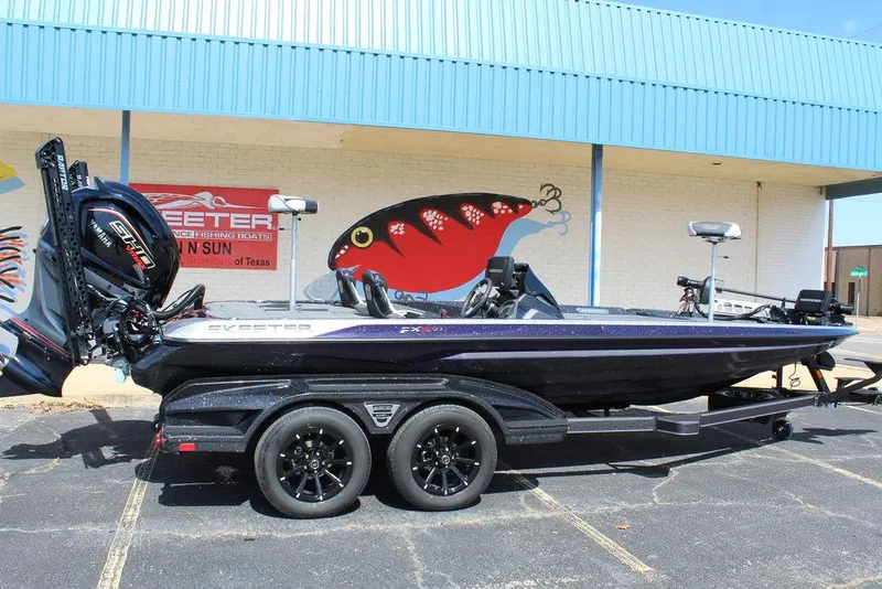 Slide: The Image of 2025 Skeeter FXR21L boat on trailer, parked outside a building with fishing mural. - 3