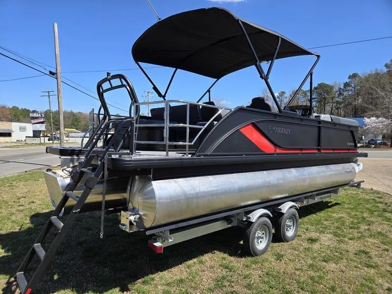Slide: The Image of 2025 Godfrey Sweetwater 2286 SFLC pontoon boat with canopy on a trailer, parked outdoors. - 11