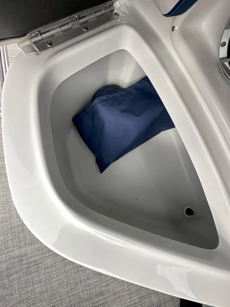 Slide: The Image of 2025 Crownline E235 storage compartment with blue cover inside. - 10