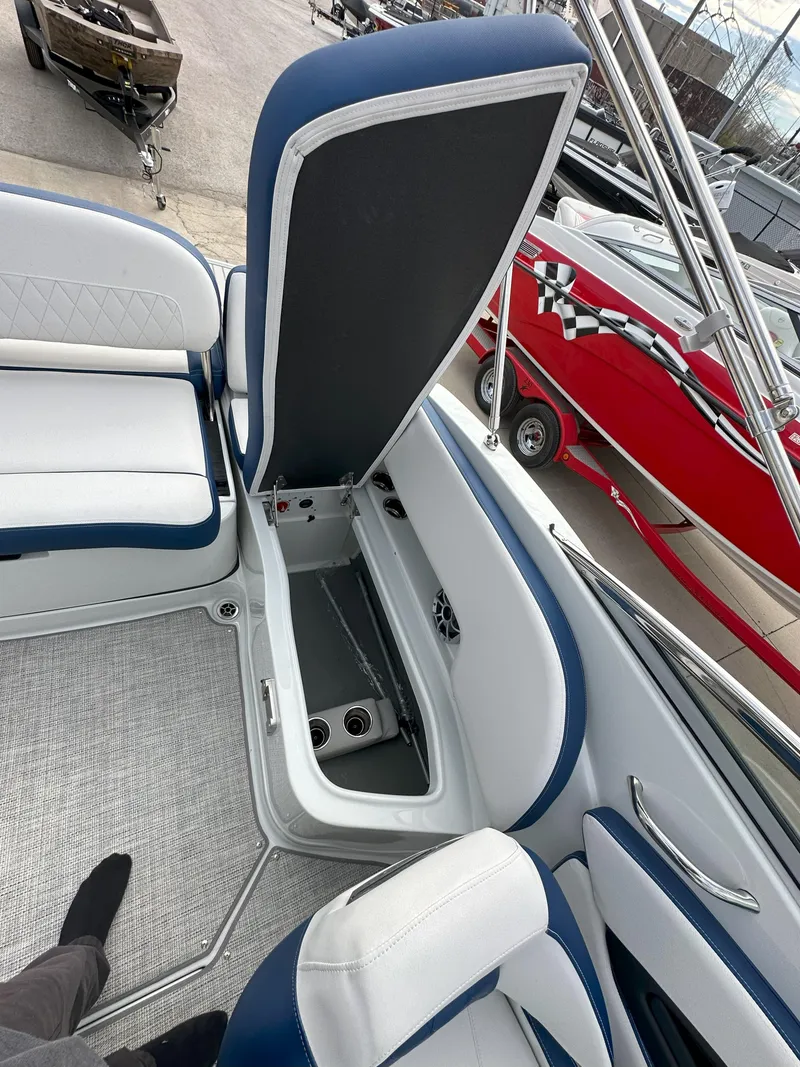 Slide: The Image of 2025 Crownline E235 boat interior with open storage compartment, blue and white seating. - 11