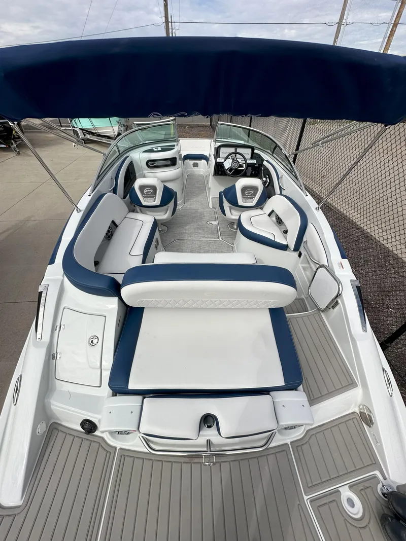Slide: The Image of 2025 Crownline E235 boat with blue and white seating, spacious deck, and canopy. - 5