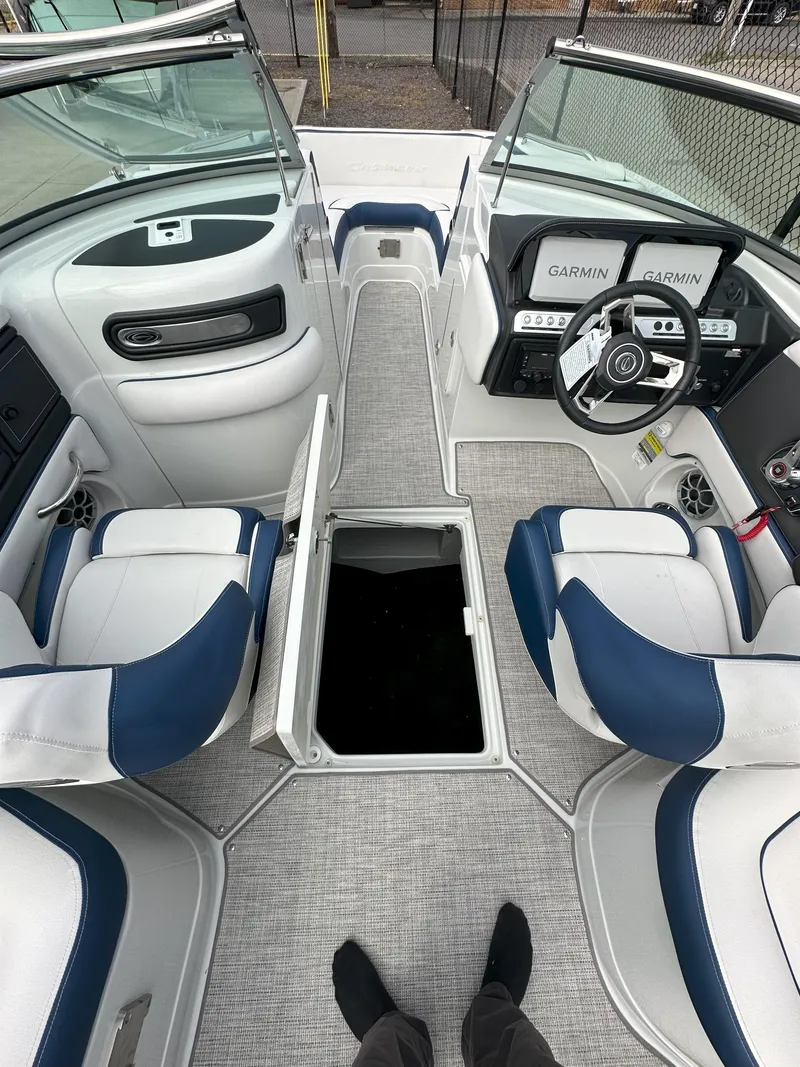 Slide: The Image of 2025 Crownline E235 boat interior with open storage, blue and white seating, and modern dashboard. - 7