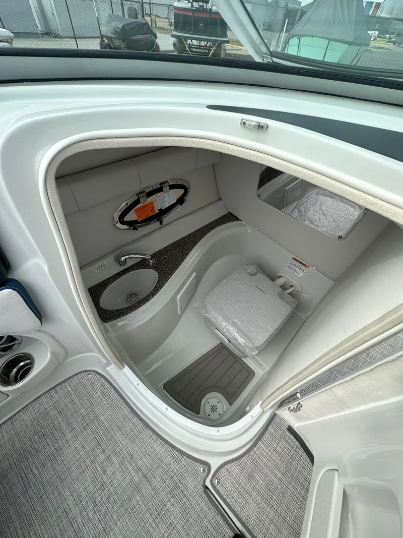 Slide: The Image of 2025 Crownline E235 boat interior with compact bathroom and modern amenities. - 8