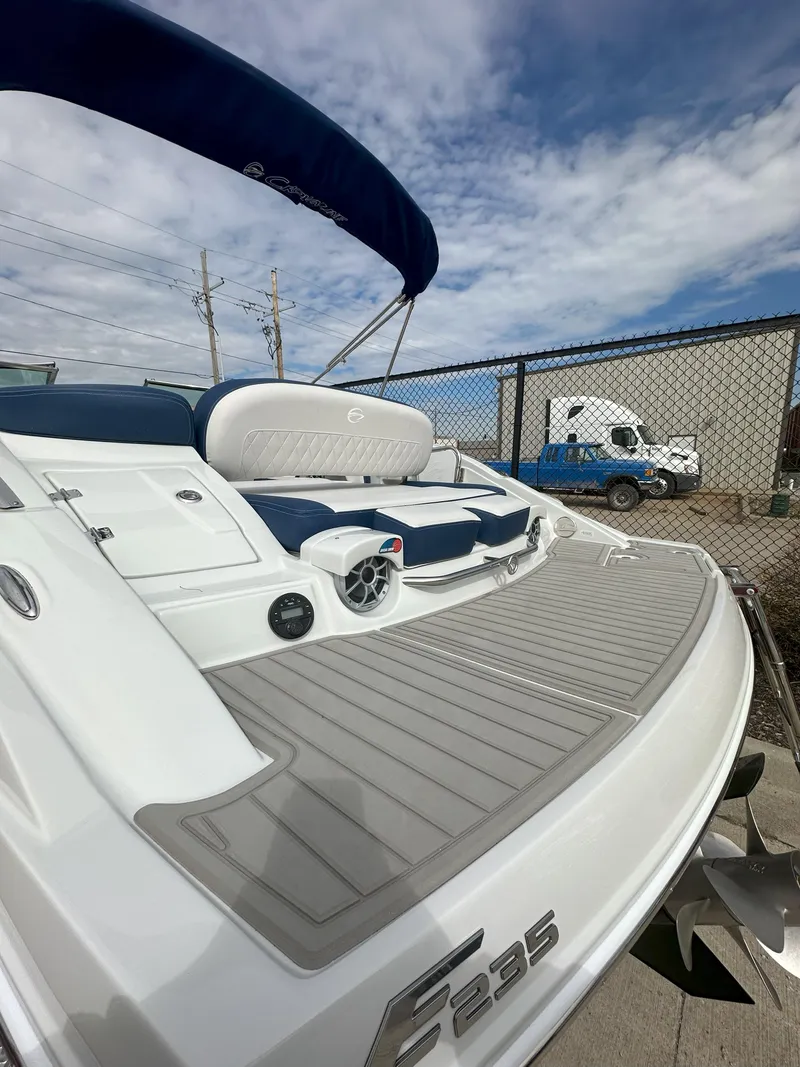 Slide: The Image of 2025 Crownline E235 boat with sleek design and spacious deck under a blue sky. - 9