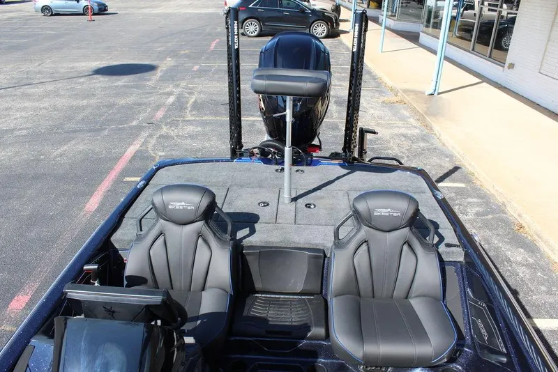 Slide: The Image of 2025 Skeeter ZXR20 boat interior with dual seats and motor, parked in a lot. - 16