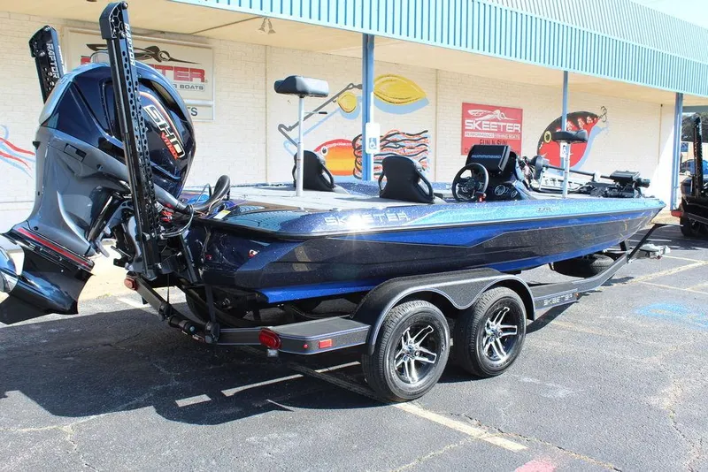 Slide: The Image of 2025 Skeeter ZXR20 bass boat with dual axle trailer, parked outside a dealership. - 2