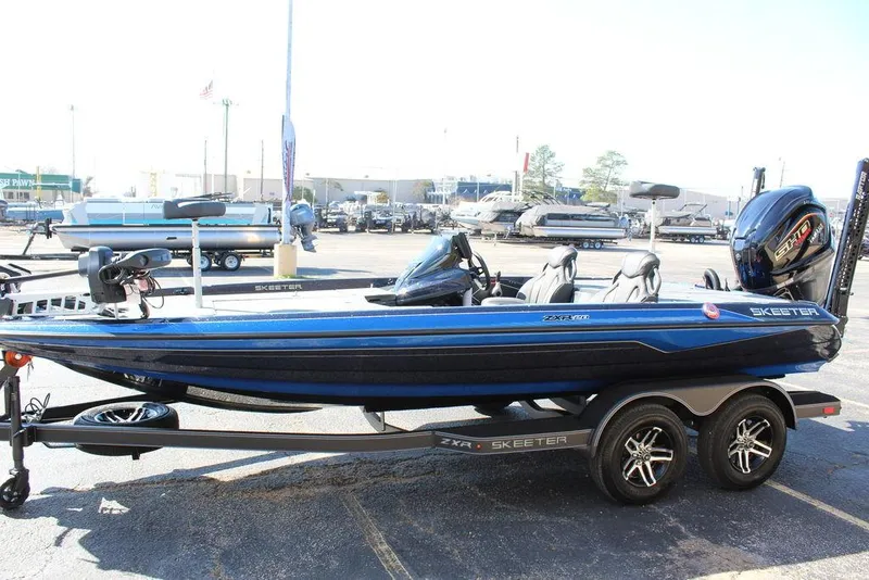 Slide: The Image of 2025 Skeeter ZXR20 bass boat on trailer, blue and black design, parked outdoors. - 6