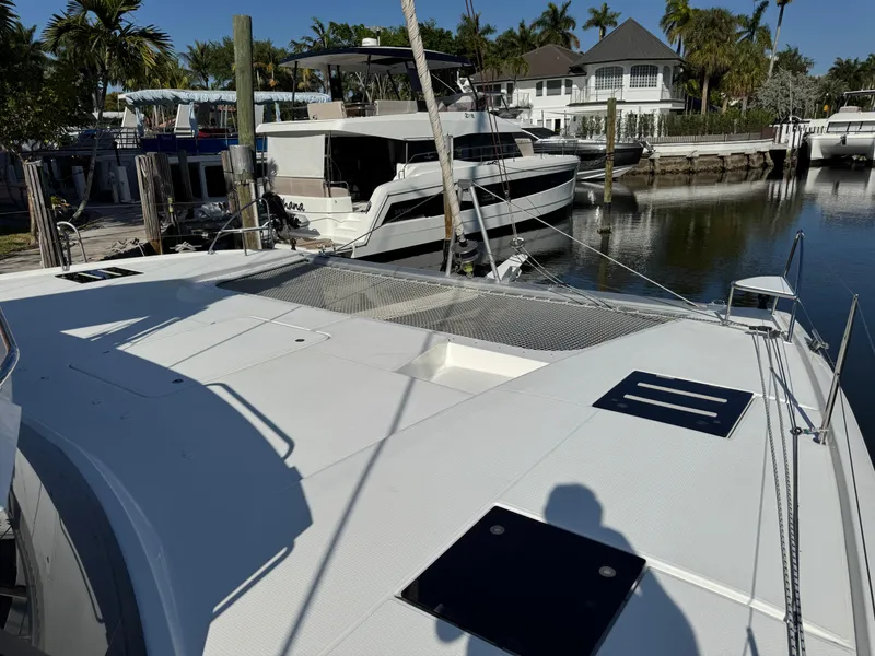 Slide: The Image of 2018 Fountaine Pajot Saona 47 catamaran docked in a marina, surrounded by palm trees. - 22