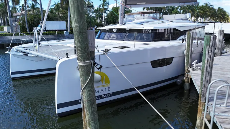 Slide: The Image of 2018 Fountaine Pajot Saona 47 catamaran docked at marina, surrounded by palm trees. - 8