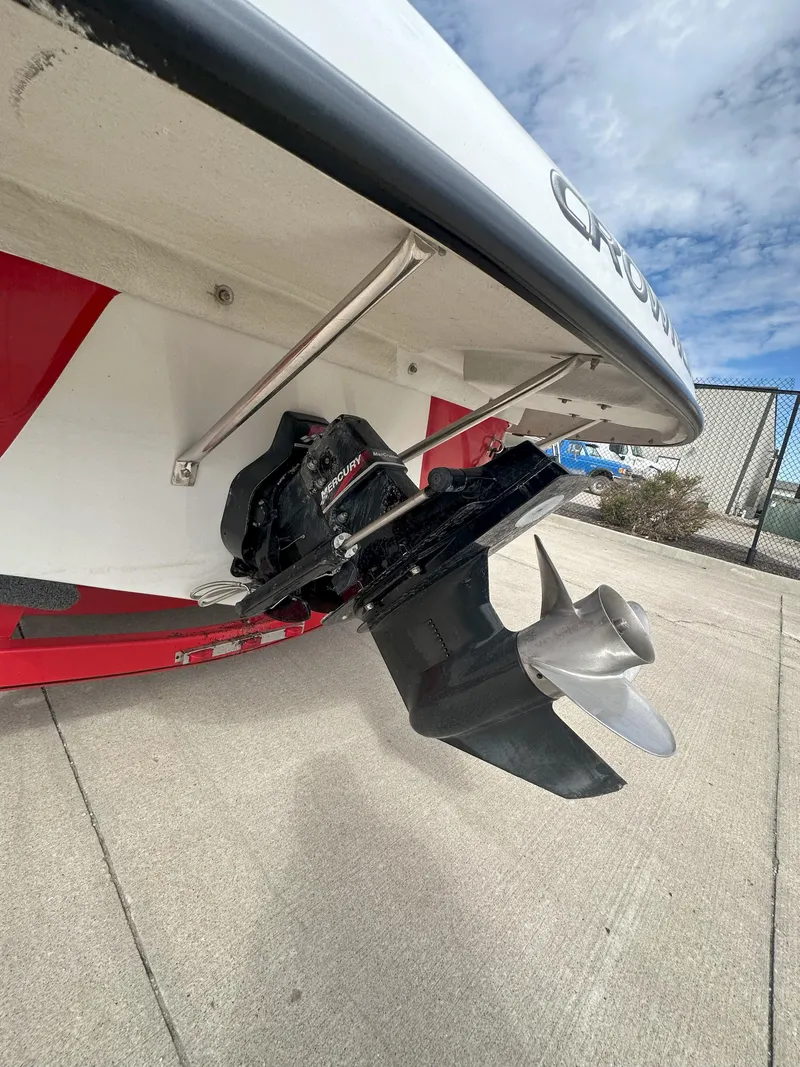 Slide: The Image of 2003 Crownline 230 boat stern with propeller, docked on concrete under a cloudy sky. - 11