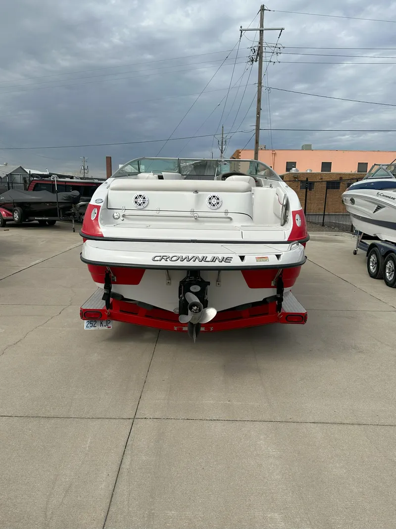 Slide: The Image of 2003 Crownline 230 boat, rear view, parked on concrete, overcast sky. - 4