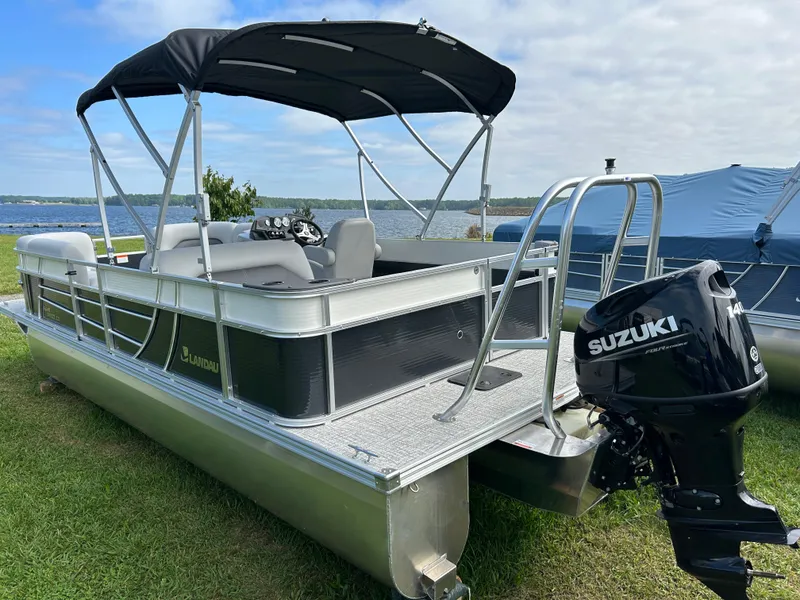 Slide: The Image of 2023 Landau Island Breeze 232 Cruise pontoon boat with Suzuki outboard motor, docked by a lake. - 7
