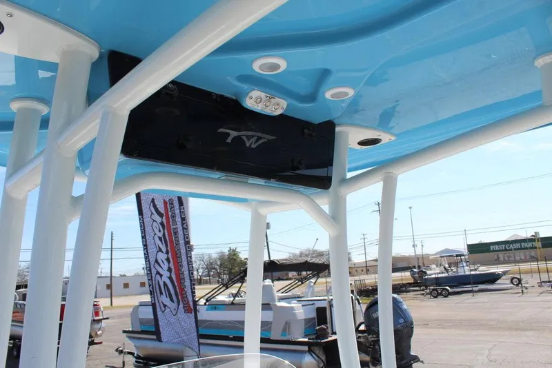 Slide: The Image of 2025 Tidewater 210 LXF boat with blue T-top and white frame in a marina setting. - 13