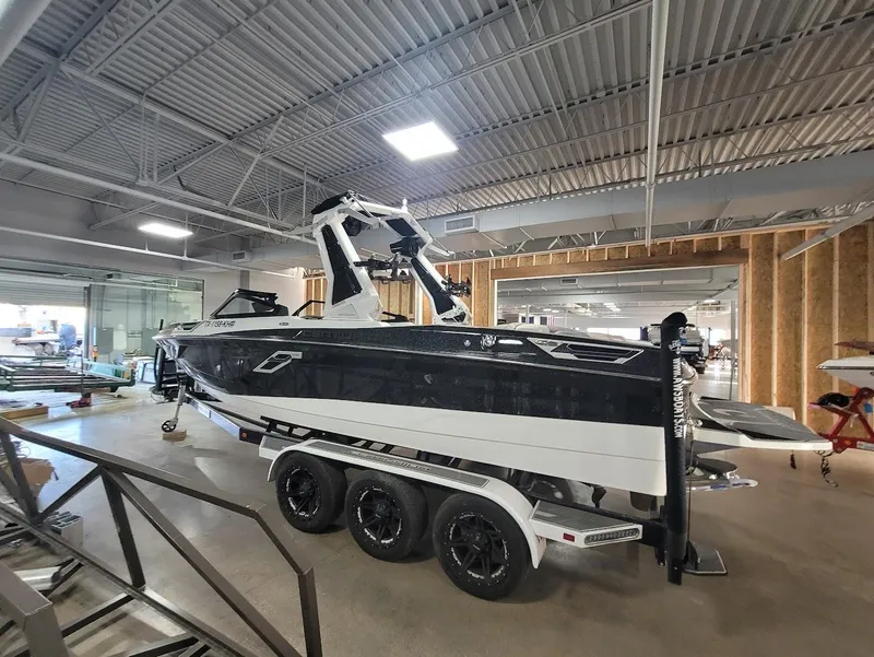 Slide: The Image of 2021 Centurion Ri245 boat on a trailer in a showroom, featuring a sleek black and white design. - 1