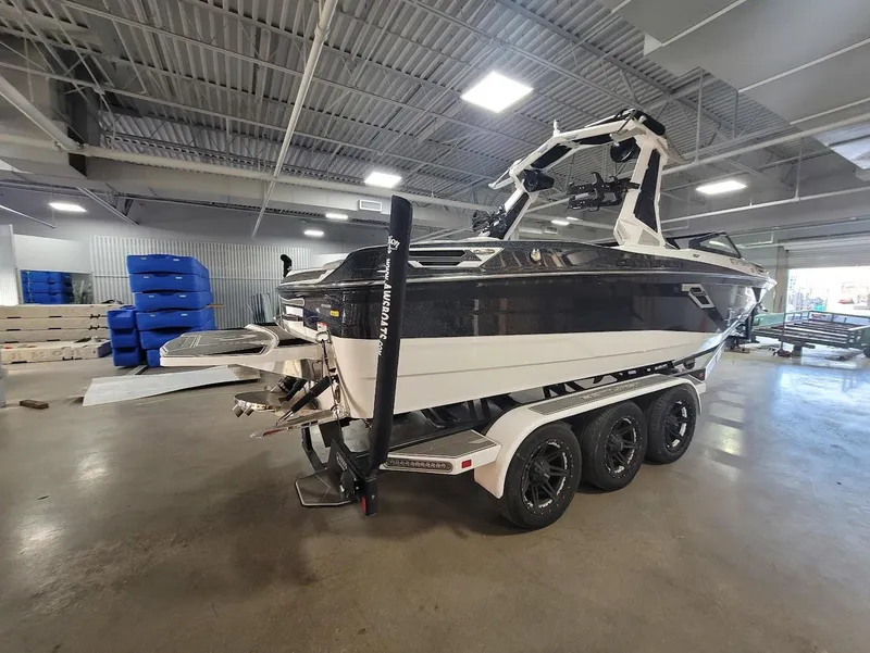 Slide: The Image of 2021 Centurion Ri245 boat in showroom, black and white design, triple-axle trailer. - 4