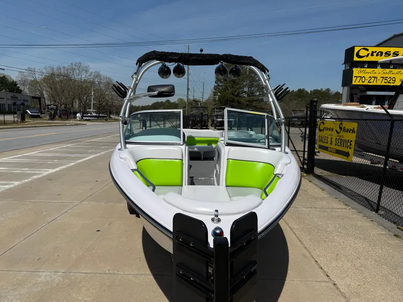 Slide: The Image of 2007 Nautique Air SV-211 boat with green seating, parked outdoors on a sunny day. - 2