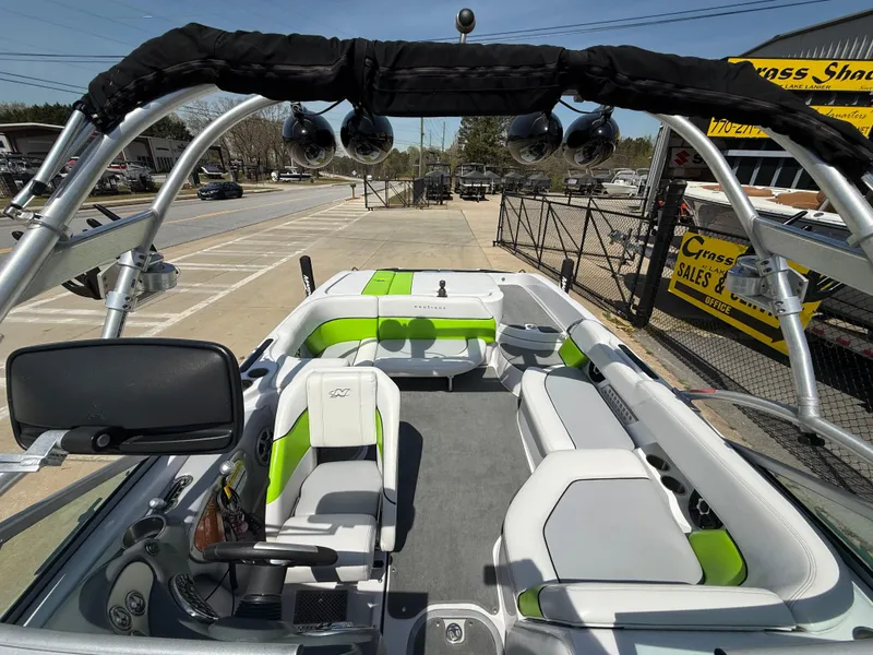 Slide: The Image of 2007 Nautique Air SV-211 boat interior with green and white seating, parked near a sales shop. - 21