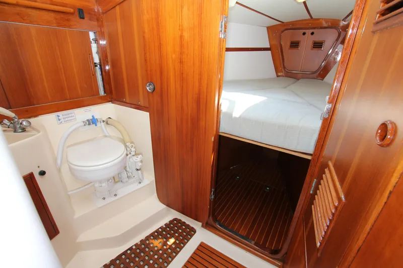 Slide: The Image of 1974 Nautor Swan 38 yacht interior with wooden finish, featuring a compact bathroom and cozy sleeping area. - 18