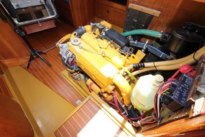 Slide: The Image of Engine room of a 1974 Nautor Swan 38 sailboat, featuring a yellow engine and wooden flooring. - 32