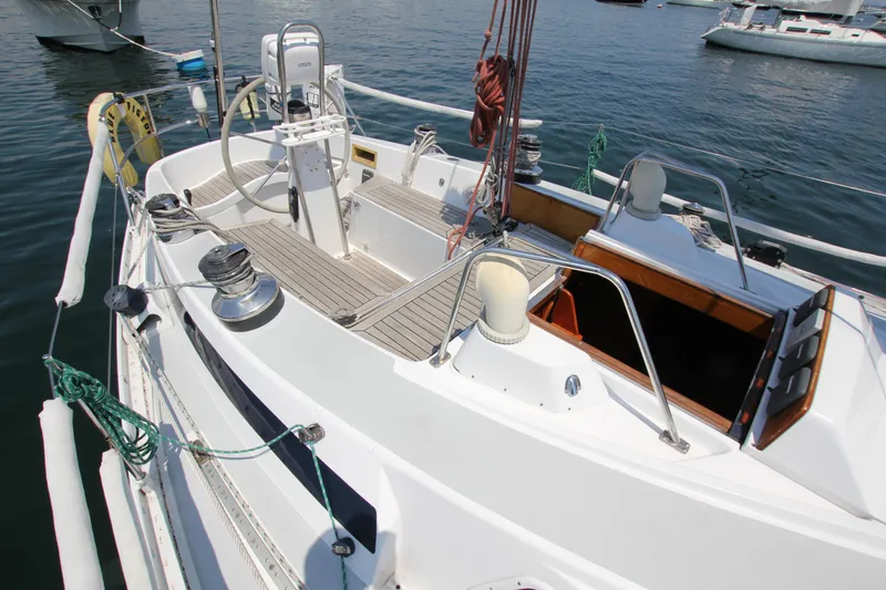 Slide: The Image of 1974 Nautor Swan 38 sailboat deck with steering wheel and winches, docked in a marina. - 8