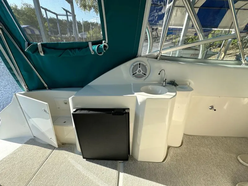 Slide: The Image of 1995 Cruisers Yachts 3175 Rogue interior with mini fridge and sink, featuring green canopy. - 7