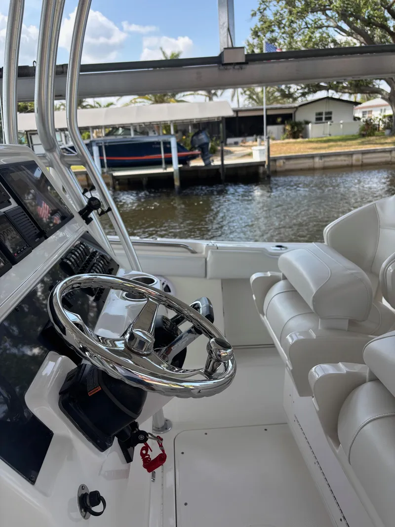 Slide: The Image of 2015 Robalo R300 Center Console boat interior with steering wheel and seating, dockside view. - 10