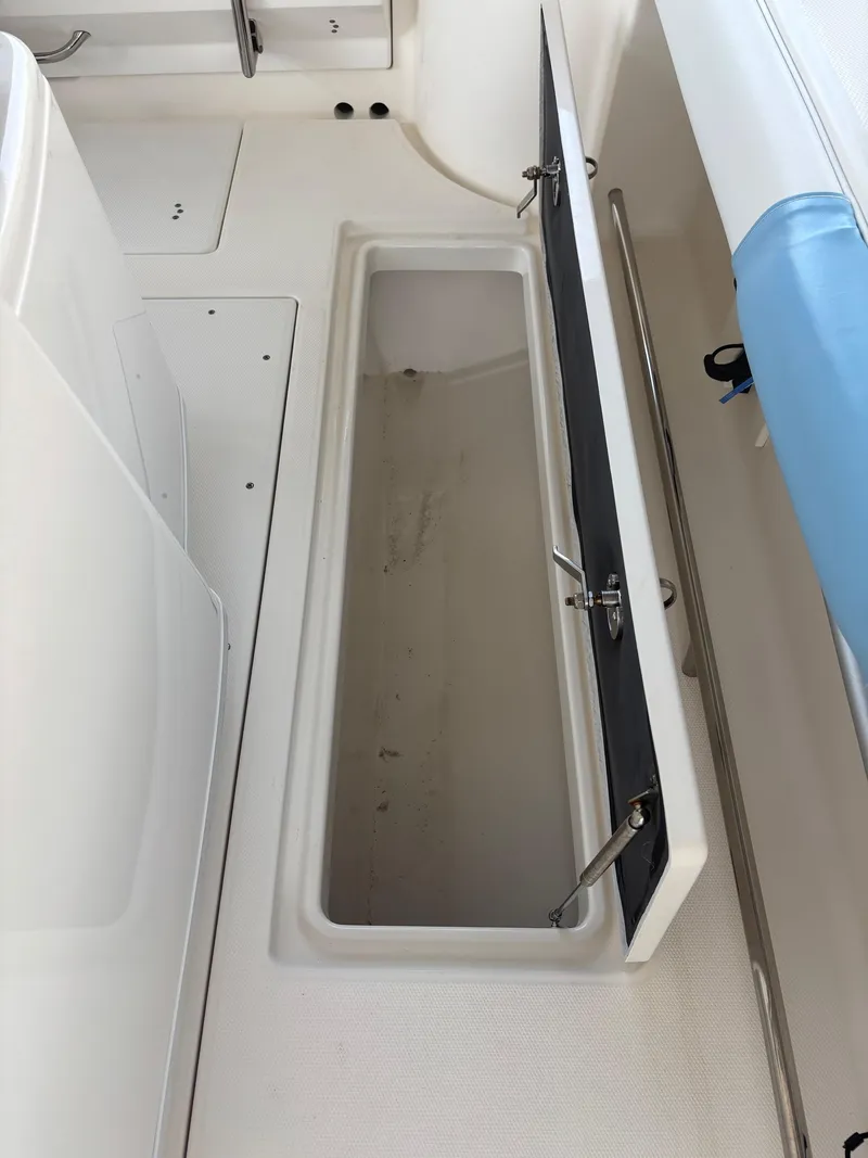Slide: The Image of 2015 Robalo R300 Center Console storage compartment with open lid, showcasing interior space. - 14