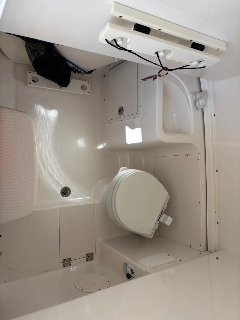 Slide: The Image of 2015 Robalo R300 Center Console boat interior with toilet and storage compartments. - 21