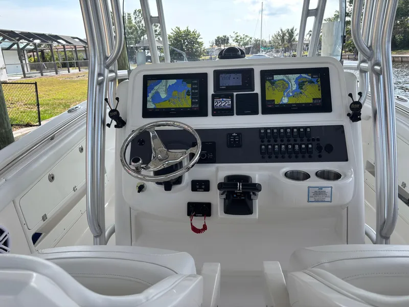 Slide: The Image of 2015 Robalo R300 Center Console boat dashboard with dual navigation screens and steering wheel. - 6