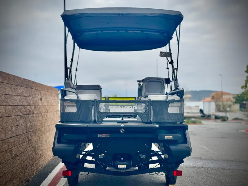 Slide: The Image of 2023 Sea-Doo Switch Cruise 18 pontoon boat, rear view with canopy, parked outdoors. - 5