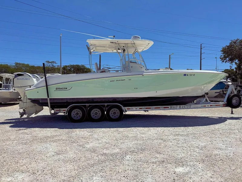 Slide: The Image of 2004 Boston Whaler 320 Outrage boat on a trailer in a parking lot. - 1