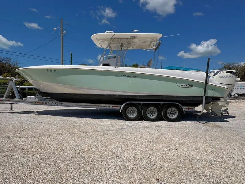 Slide: The Image of 2004 Boston Whaler 320 Outrage boat on trailer under clear blue sky. - 4