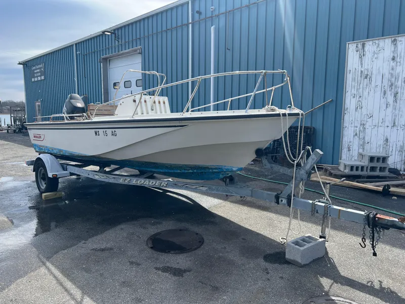 Slide: The Image of 1992 Boston Whaler 19 OUTRAGE boat on trailer, parked near blue warehouse. - 4