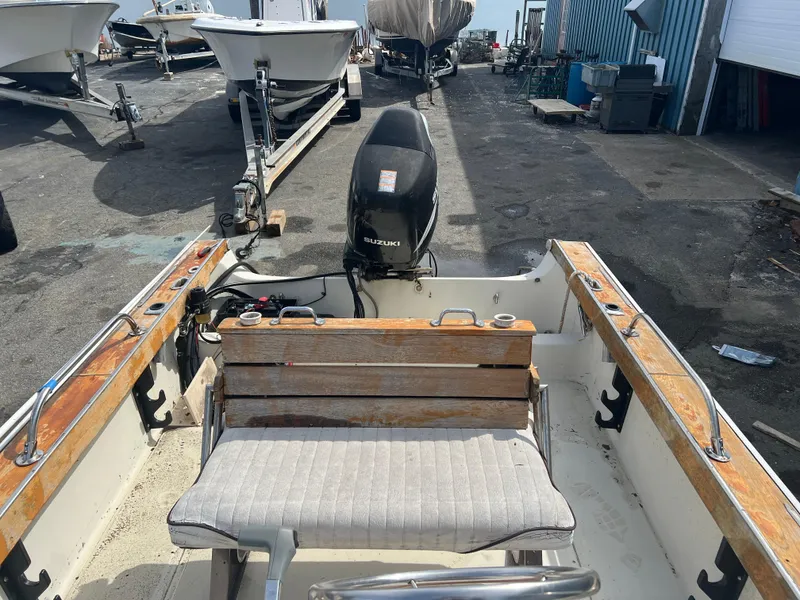 Slide: The Image of 1992 Boston Whaler 19 Outrage boat with Suzuki outboard motor, docked in a marina. - 7