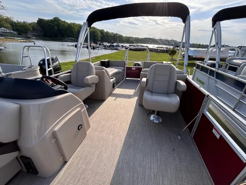 Slide: The Image of 2024 Landau Island Breeze 232 Cruise pontoon boat with spacious seating, docked by a scenic lake. - 4
