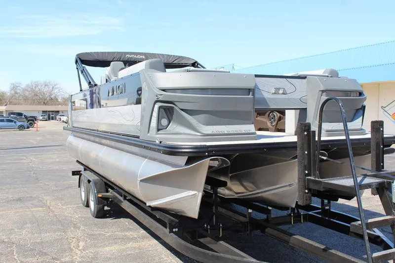 Slide: The Image of 2025 Avalon GEO FISH REAR FISH pontoon boat on trailer, outdoor setting. - 11