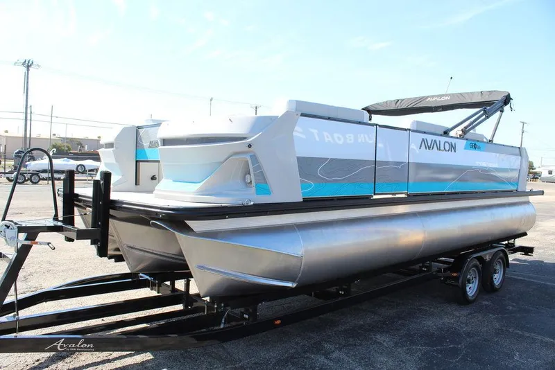 Slide: The Image of 2025 Avalon GEO FISH REAR FISH pontoon boat on trailer, sleek design, outdoor setting. - 7