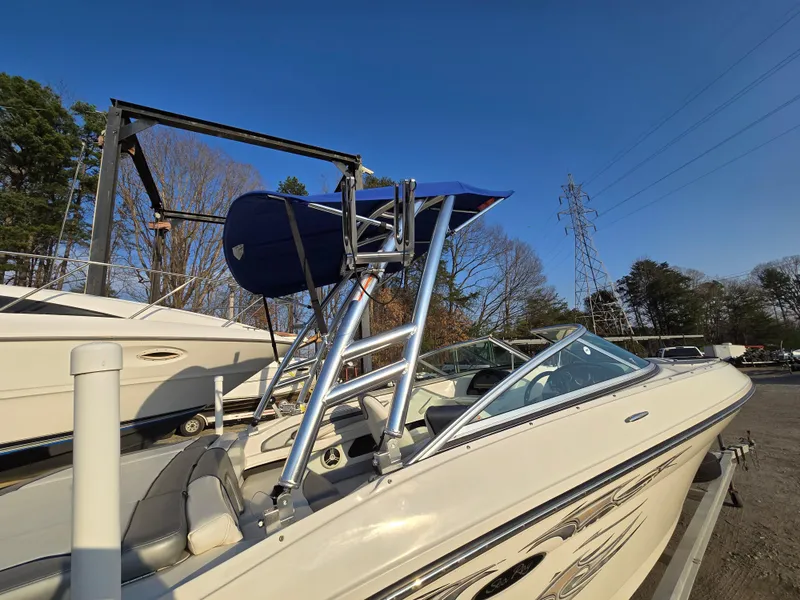 Slide: The Image of 2008 Sea Ray 205 Sport boat with blue canopy, parked outdoors under clear sky. - 19