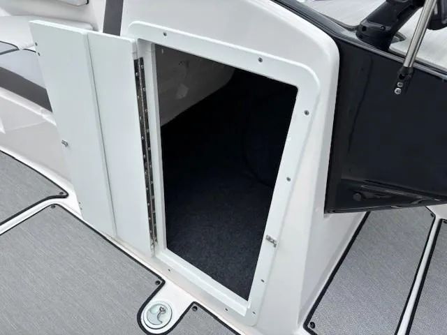 Slide: The Image of 2023 Yamaha AR220 boat storage compartment with open door, showcasing interior space. - 17