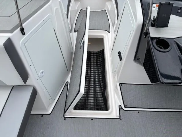 Slide: The Image of 2023 Yamaha Boats AR220 interior storage compartment with open hatch, showcasing sleek design and functionality. - 19