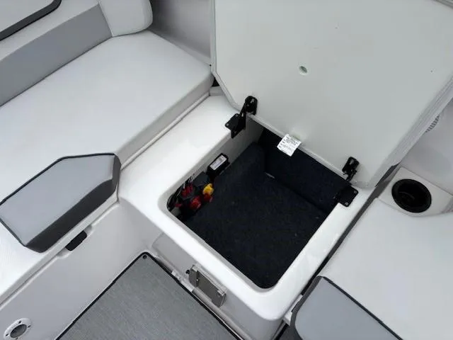 Slide: The Image of 2023 Yamaha Boats AR220 storage compartment with open lid, showcasing interior space. - 24